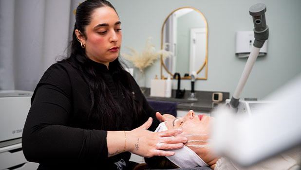Woman esthetician applying a facial treatment to a client in a spa treatment room