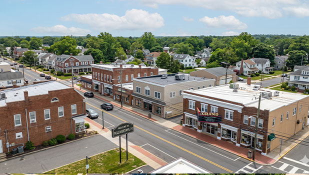 Aerial view of a small town downtown with brick storefronts, tree-lined streets, and a residential neighborhood