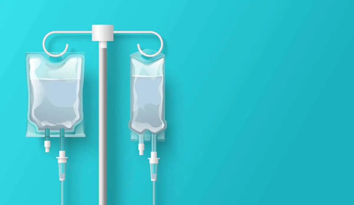 Two intravenous fluid bags hanging from an IV pole against a teal medical background